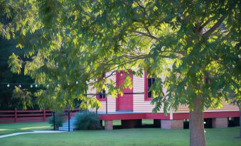 a red and white house with a red door is nestled under a tree on a grassy field at Coulter Farmstead