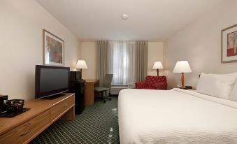 a well - lit hotel room with a bed , tv , desk , and window , all decorated in white and green colors at Country Inn & Suites by Radisson, Fairview Heights, IL