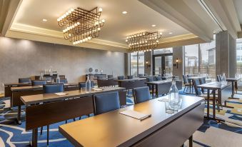 a modern conference room with wooden tables , blue carpeting , and large windows , as well as chandeliers hanging from the ceiling at Hotel Centro Sonoma Wine Country, Tapestry by Hilton