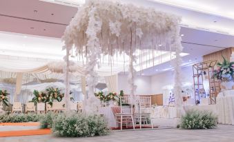 a large white wedding reception with a canopy made of flowers and greenery , creating a festive atmosphere at Grand Cordela Hotel As Putra Kuningan