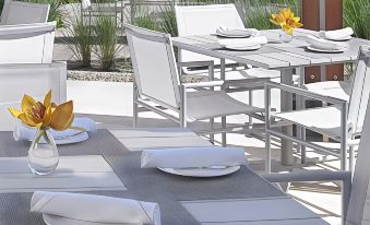 a table set with white plates , napkins , and glasses on a patio area surrounded by chairs at Grand Beach Hotel Bay Harbor