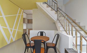 a modern dining room with a wooden table and black chairs , situated near a staircase at RedDoorz Plus Near Uin Raden Fatah Palembang