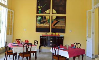 a dining room with yellow walls , a red tablecloth , and several chairs arranged around it at Hostal la Casona