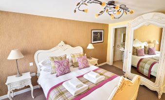 a luxurious bedroom with a white bed , gold walls , and pink and purple pillows on it at The George Hotel