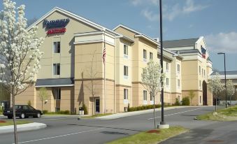 a fairfield inn & suites hotel with its sign , surrounded by trees and a street with cars parked on the side at Fairfield Inn & Suites Worcester Auburn