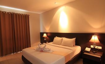 a large bed with a white comforter and two pillows is in a room with a lamp on the nightstand at Hotel Bonero Residence
