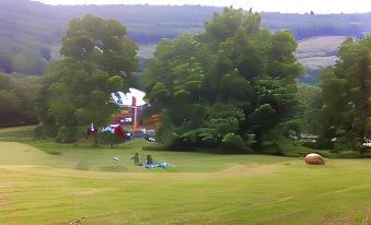 a group of people enjoying a sunny day at a golf course , surrounded by green grass and trees at Shaw Mansion Inn