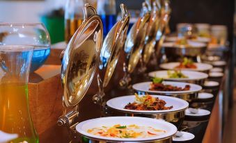 a buffet table filled with a variety of food items , including bowls of soup and other dishes at Palm Seremban Hotel