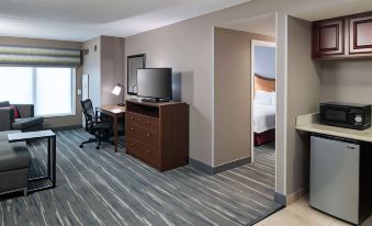 a hotel room with a tv , desk , and chair , as well as a bedroom with a bed at Hampton Inn & Suites Chicago North Shore
