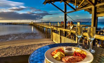 a dining table with a plate of food and a glass of wine on it , overlooking the ocean at Kingfisher Bay Resort