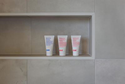 three white tubes with red and blue text on them are lined up in a white shelf at Oval Hotel at Adelaide Oval, an EVT hotel
