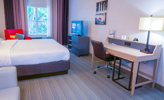 a hotel room with a bed , desk , and tv , along with various amenities such as a chair and television at Country Inn & Suites by Radisson, Burlington (Elon), NC