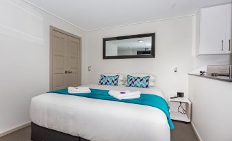a clean and well - organized bedroom with a white bed , a blue comforter , and a mirror on the wall at Hamilton on Beaumont