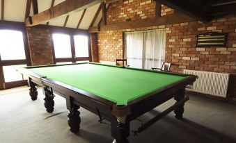 a large green pool table in a room with brick walls and a brick wall at Bluebell Farm