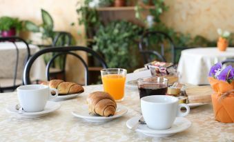 a table is set with breakfast items , including croissants and orange juice , along with cups of coffee at Hotel Sole