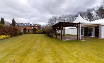 a grassy field with a gazebo and a white building in the background , creating a picturesque scene at Nunsmere Hall Hotel