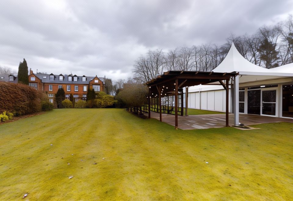 a large grassy area with a wooden shelter and a white tent in the background at Nunsmere Hall Hotel