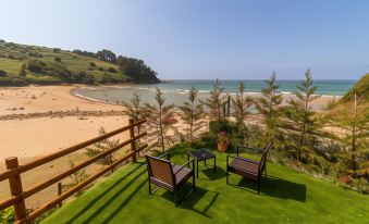 a beautiful outdoor patio with chairs and a table , overlooking a sandy beach and the ocean at Hotel SanMar