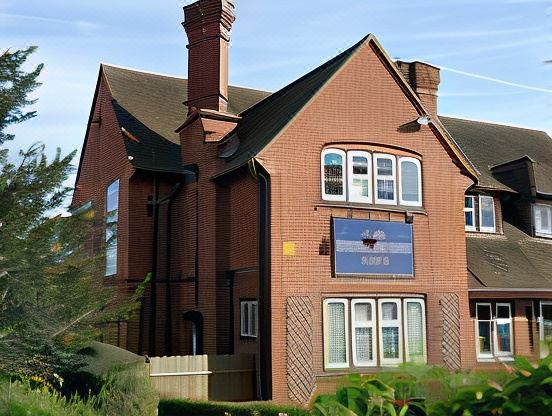 "a red brick house with a chimney and a sign that says "" peter schell "" on it" at The Baskerville