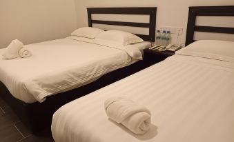 a hotel room with two beds , one on the left and one on the right , both covered in white sheets at Hotel Sri Bernam