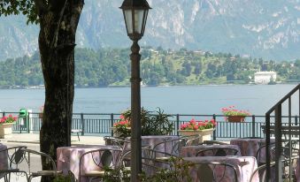 a picturesque outdoor dining area near a lake , with tables and chairs arranged for guests to enjoy a meal at Hotel Bazzoni