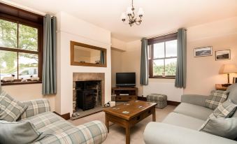 a cozy living room with a fireplace , two couches , and a tv . also a dining table in the room at Stanley Lodge Farmhouse