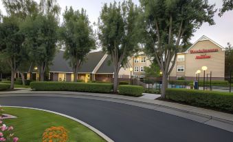a large building with a swimming pool and trees in front of it , under the shade of trees at Residence Inn Stockton