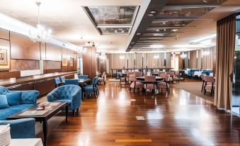 a large dining room with wooden floors and tables , blue chairs , and pink chairs , as well as chairs placed around the tables at Hotel Holiday