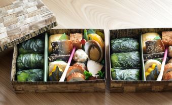 a wooden box filled with various types of sushi , including rolls , sashimi , and rolls , placed on a dining table at Fairfield by Marriott Mie Kumano Kodo Mihama