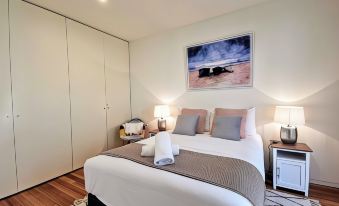 a cozy bedroom with a white bed , two lamps , and a painting on the wall at Phoenix Apartments