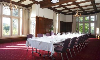 a long table with a white tablecloth and purple chairs is set up in a large room at Woodland Grange