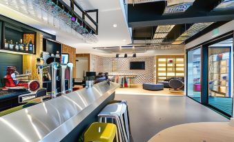 a modern bar with a long counter , multiple stools , and various beer taps , creating an inviting atmosphere for patrons at Campanile Laval Nord