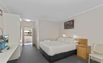 a clean , well - organized bedroom with a white bed and a black dresser in the corner at Discovery Parks - Townsville