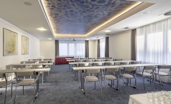 a conference room with chairs arranged in rows and a blue ceiling , creating a cozy and inviting atmosphere at Hotel Continental