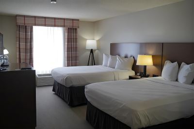 a hotel room with two beds , each made with white sheets and pillows , next to each other at Country Inn & Suites by Radisson, Watertown, SD