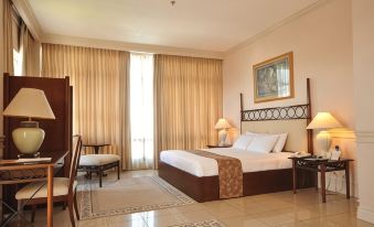 a well - decorated hotel room with a large bed , curtains , and various furniture items , including a desk , chair , and lamp at MetroCentre Hotel
