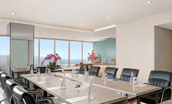 a modern conference room with a large table and several chairs arranged for a meeting at Golden Tulip SpringHill Lampung