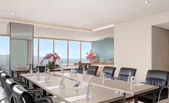 a modern conference room with a long table and multiple chairs , surrounded by large windows offering views of the ocean at Golden Tulip SpringHill Lampung