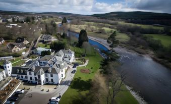 aerial view of a large house surrounded by a golf course , with a river flowing nearby at Banchory Lodge Hotel