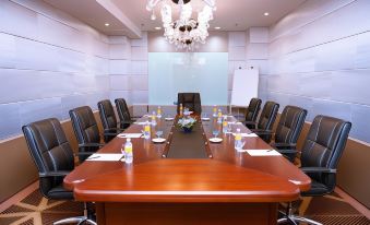 a conference room with a long wooden table , chairs , and a chandelier hanging from the ceiling at Palm Seremban Hotel