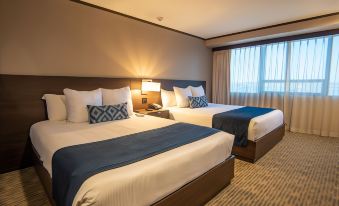 a hotel room with two beds , one on the left and one on the right side of the room at Grand Hotel Tijuana