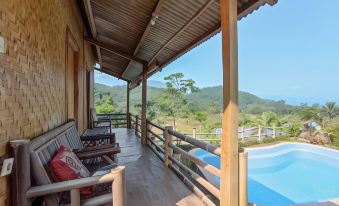 a wooden porch with a view of a pool and mountains , featuring several chairs and benches at De Salak Homestay