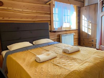 a cozy bedroom with a wooden floor , a bed covered in a yellow blanket , and several pillows placed on the bed at Troll