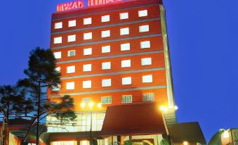 "a tall building with a red and white sign that reads "" jinwan hotel "" is shown at night" at Merapi Merbabu Hotels Bekasi