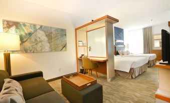 a modern hotel room with a bed , desk , and couch , as well as a painting on the wall at SpringHill Suites Grand Forks