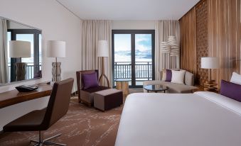 a modern hotel room with a large window offering a view of the ocean , a couch , chairs , and a bed at Park Chalet, Shahdag, Autograph Collection