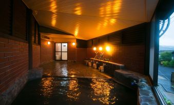 a room with a large , empty bathtub filled with water and surrounded by brick walls at Yufuin Bath Satoyamasafu