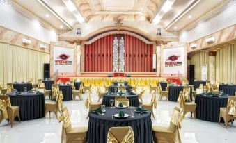 a large banquet hall with multiple round tables covered in black tablecloths and chairs arranged around them at Surya Yudha Hotel