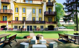 a large yellow house surrounded by a grassy field , with a deck in front of it at Hotel Bella