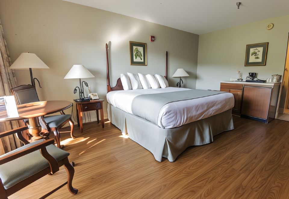 a large bed with white linens is in a room with wooden floors and two lamps at Pine Mountain State Resort Park